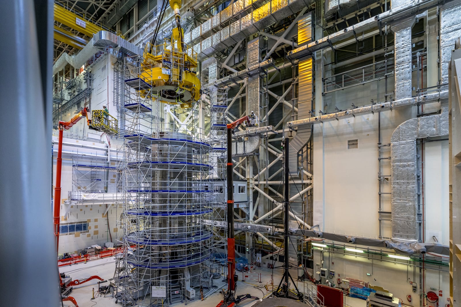 The uppermost central-solenoid module is lifted into position above the ITER magnet stack.
